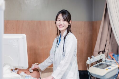 病院のベッドの上で産婦人科医さんに診察してもらっている妊婦さん